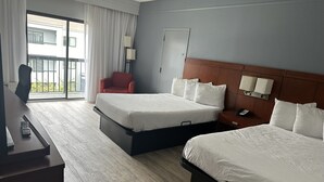 A hotel room with two beds, a desk, a chair, a TV, and a balcony with a view of buildings. - Super 8 by Wyndham Dallas Love Field Airport (Dallas)