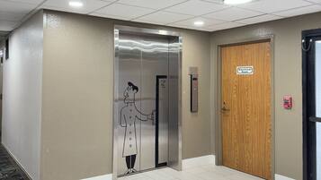 An elevator with a cartoon character, a wooden door, and a fire alarm.