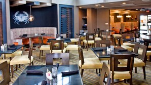 A restaurant with booths and tables, a large crab mural, and a patterned carpet.