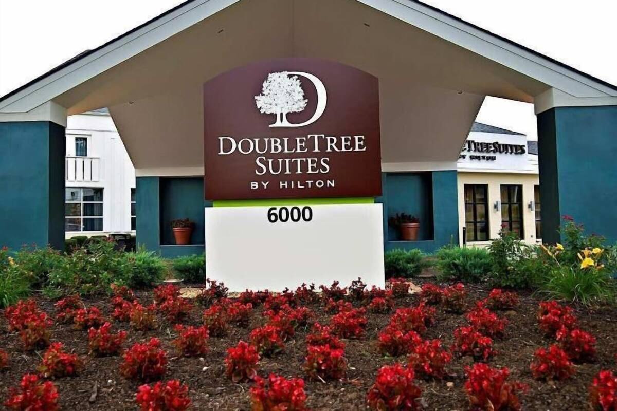 Een hotelschild voor DoubleTree Suites by Hilton met een boomlogo, het getal '6000' eronder en een overdekte ingang.