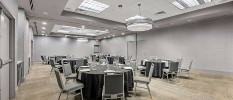 A conference room with round tables, chairs, and a carpeted floor.