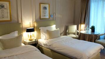 Ein Hotelzimmer mit zwei Betten, einer Sitzecke mit Tisch und Stühlen und gerahmten Kunstwerken an den Wänden.