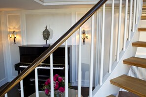 A grand piano in a well-lit room with a staircase leading to an upper floor.