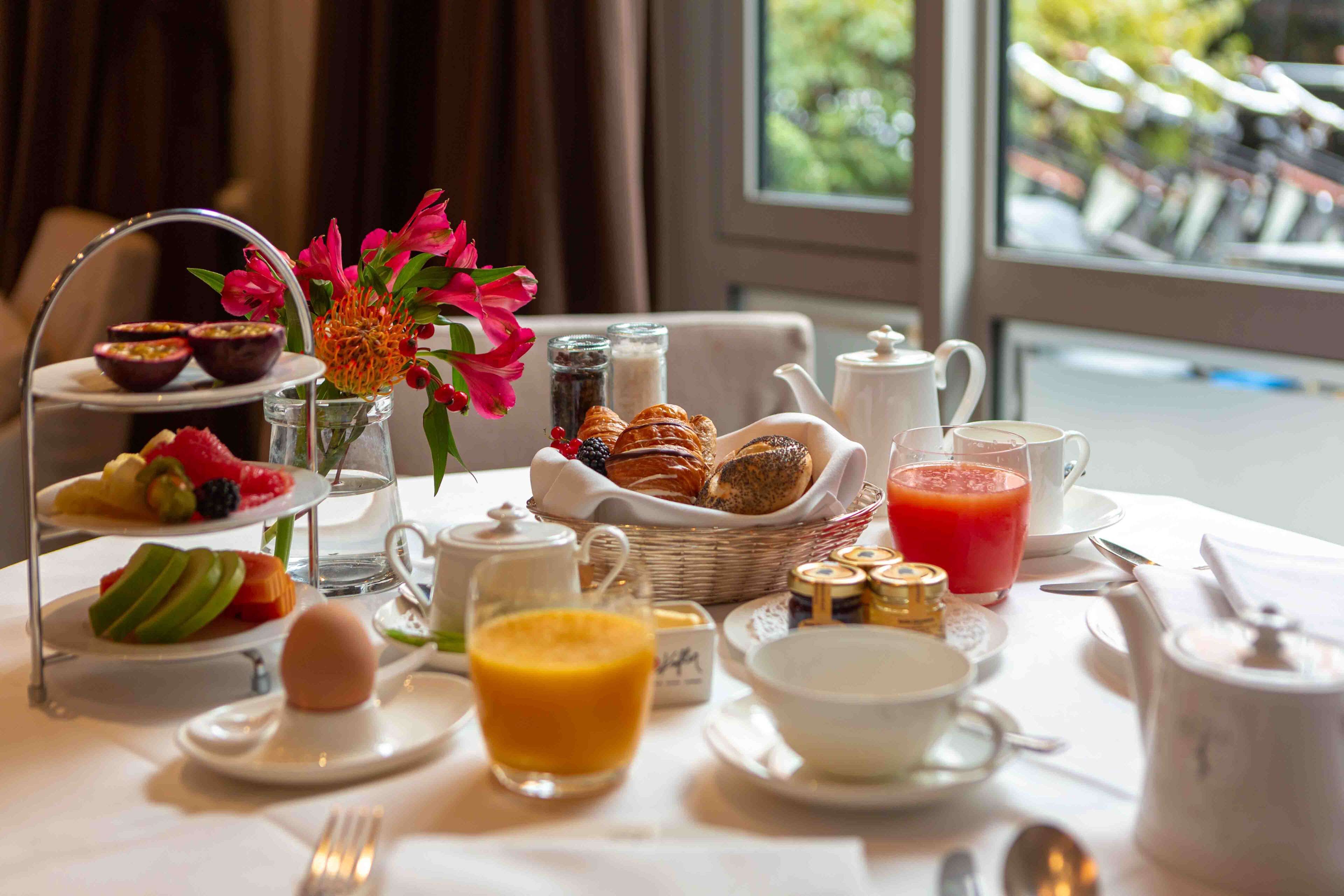 A breakfast table with various food items, including pastries, fruit, and beverages.