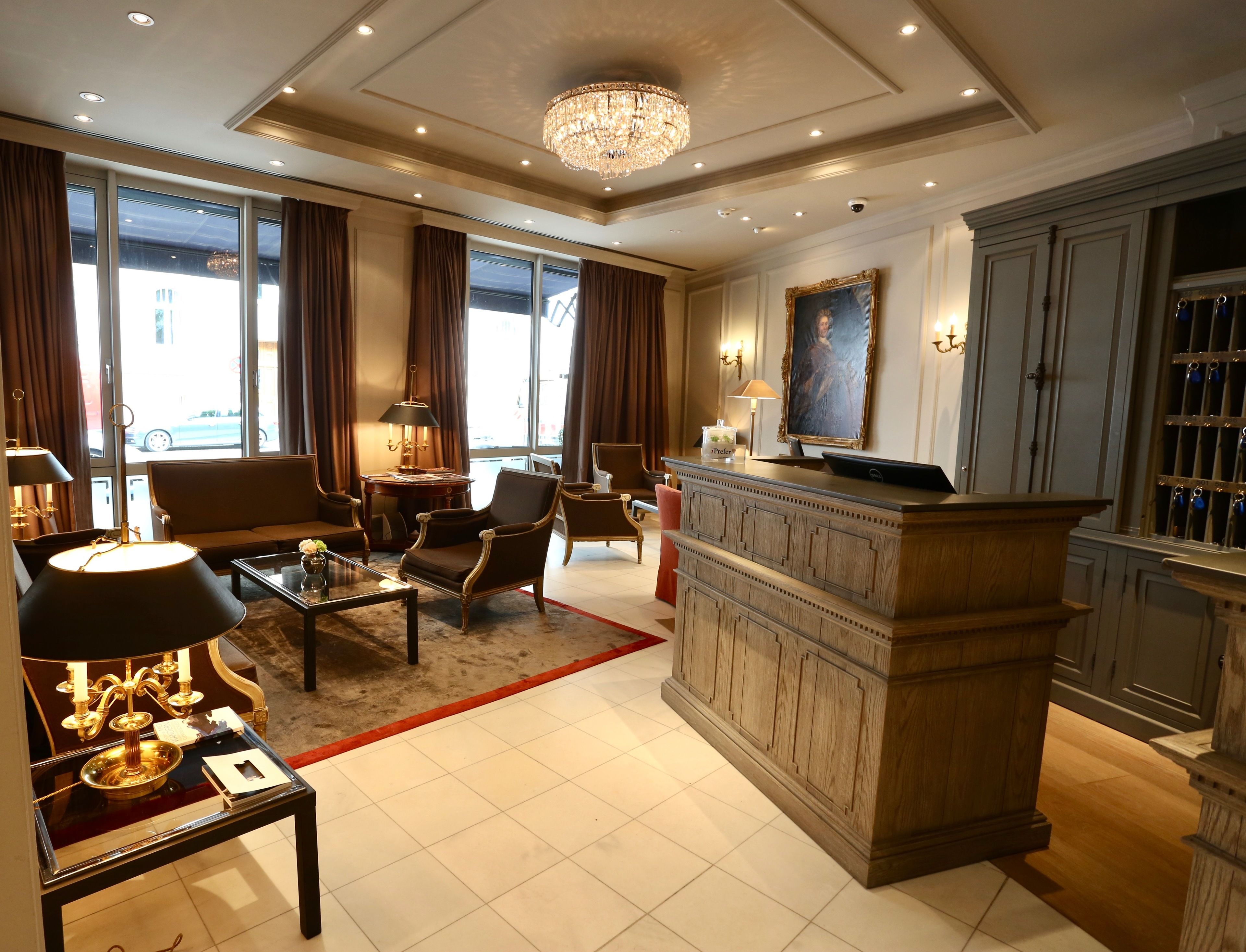 A spacious living room with a chandelier, a sofa, armchairs, a coffee table, and a desk with a lamp.