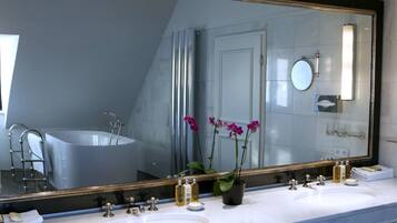 A modern bathroom with two sinks, a large mirror, and a bathtub.