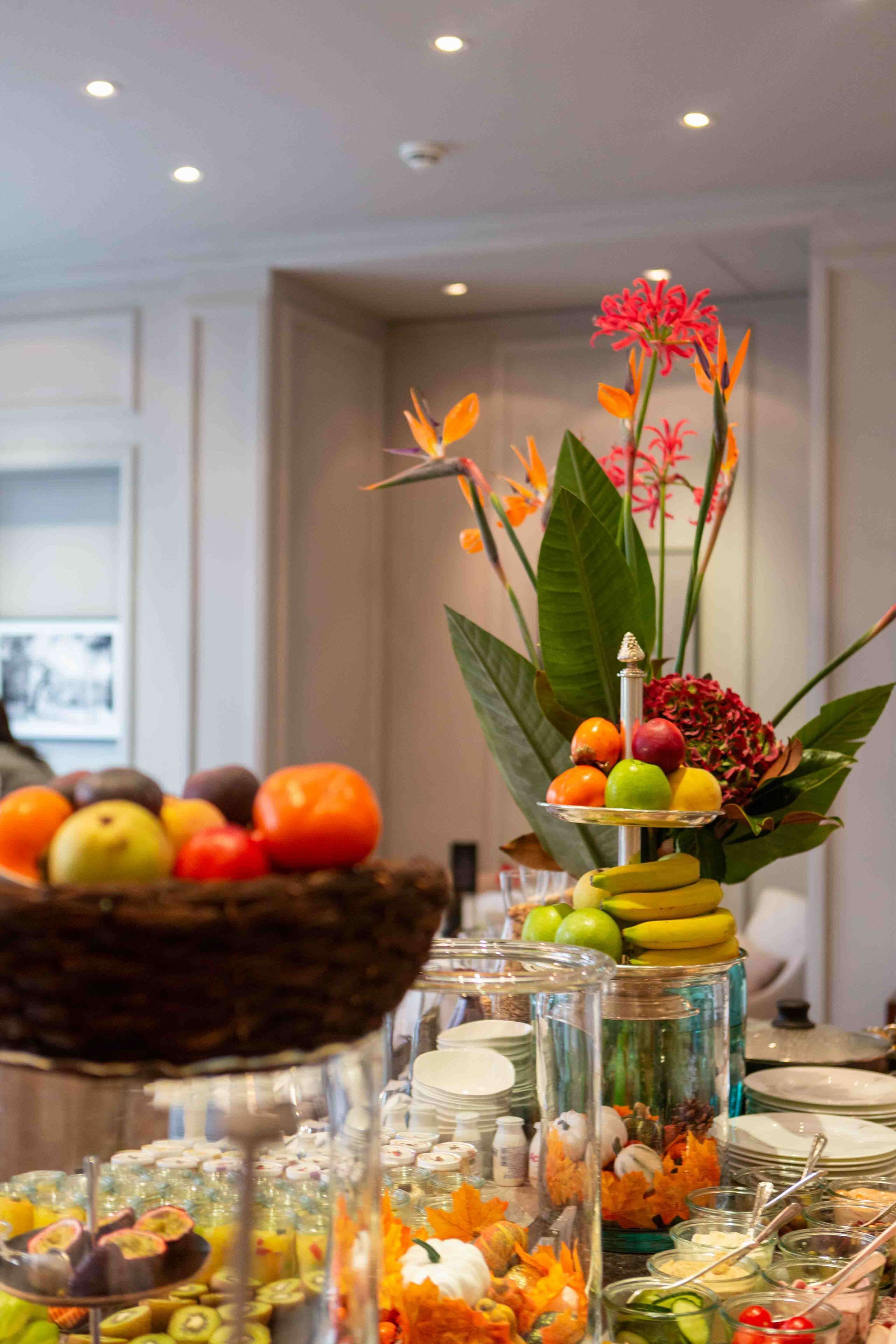 Una mesa de buffet con diversas frutas y verduras, como manzanas, naranjas y plátanos.