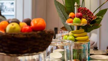 Una mesa de buffet con diversas frutas y verduras, como manzanas, naranjas y plátanos.