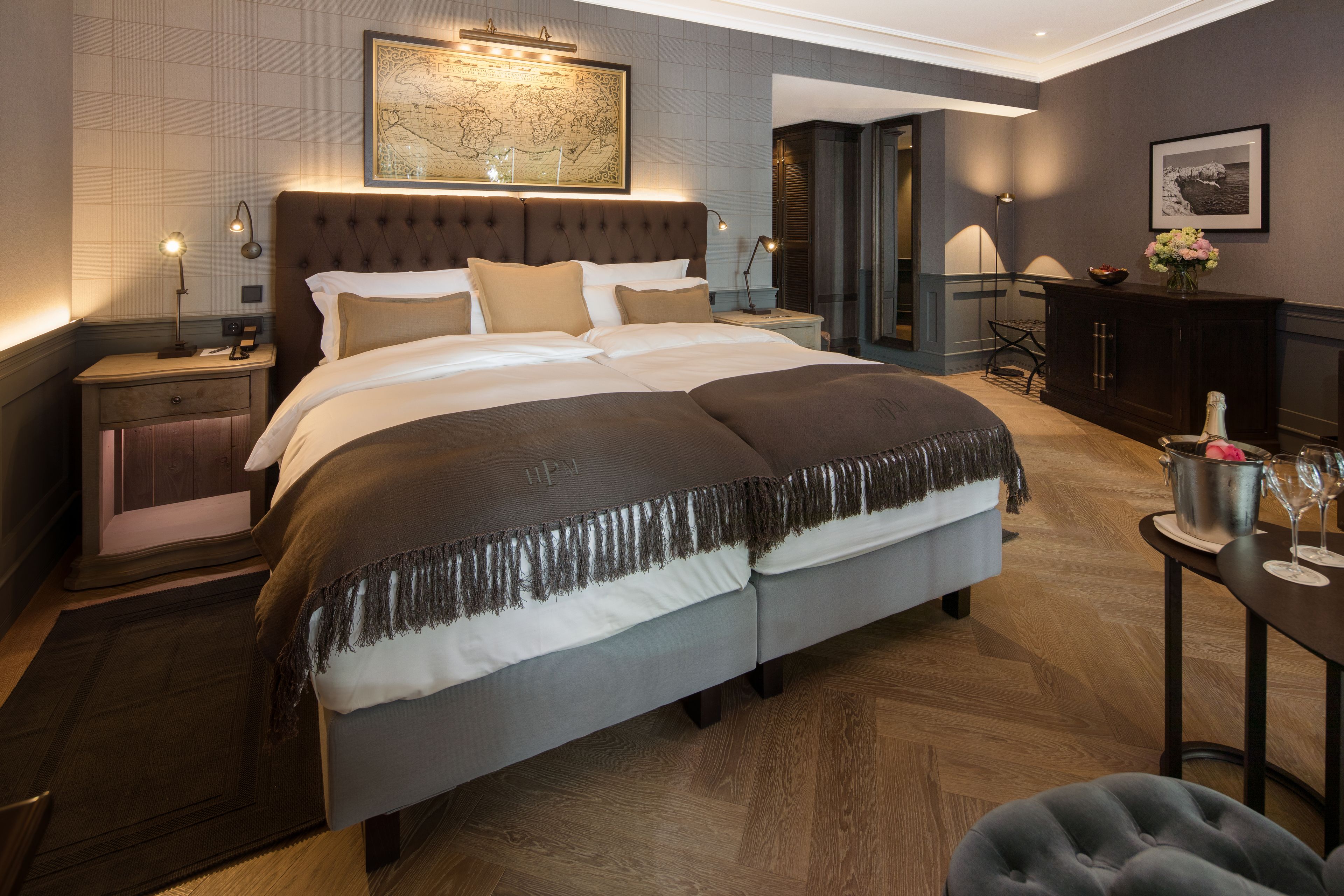 A modern hotel room with a large bed, a nightstand, a desk, and a map on the wall.