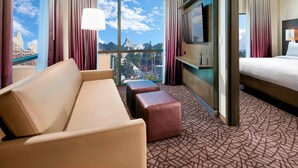 A hotel room with a large window, a sofa, a bed, a TV, and a patterned carpet. - Residence Inn by Marriott at Anaheim Resort/Convention Cntr (Anaheim)