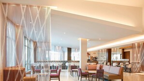 A spacious hotel lobby with a modern design, featuring a central seating area with sofas and chairs, a dining area with tables and chairs, and large windows allowing natural light. - Residence Inn by Marriott at Anaheim Resort/Convention Cntr (Anaheim)
