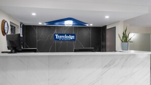 A reception desk with a marble countertop, a clock, and a sign that reads "Travelodge by Wyndham". - Travelodge by Wyndham Fargo West Acres (Fargo)
