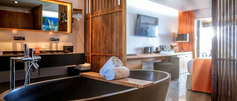 Une salle de bain moderne avec une grande baignoire noire, un meuble-lavabo en bois et un grand miroir.