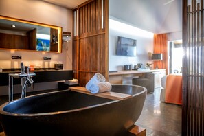 A modern bathroom with a large black bathtub, a wooden vanity, and a large mirror.