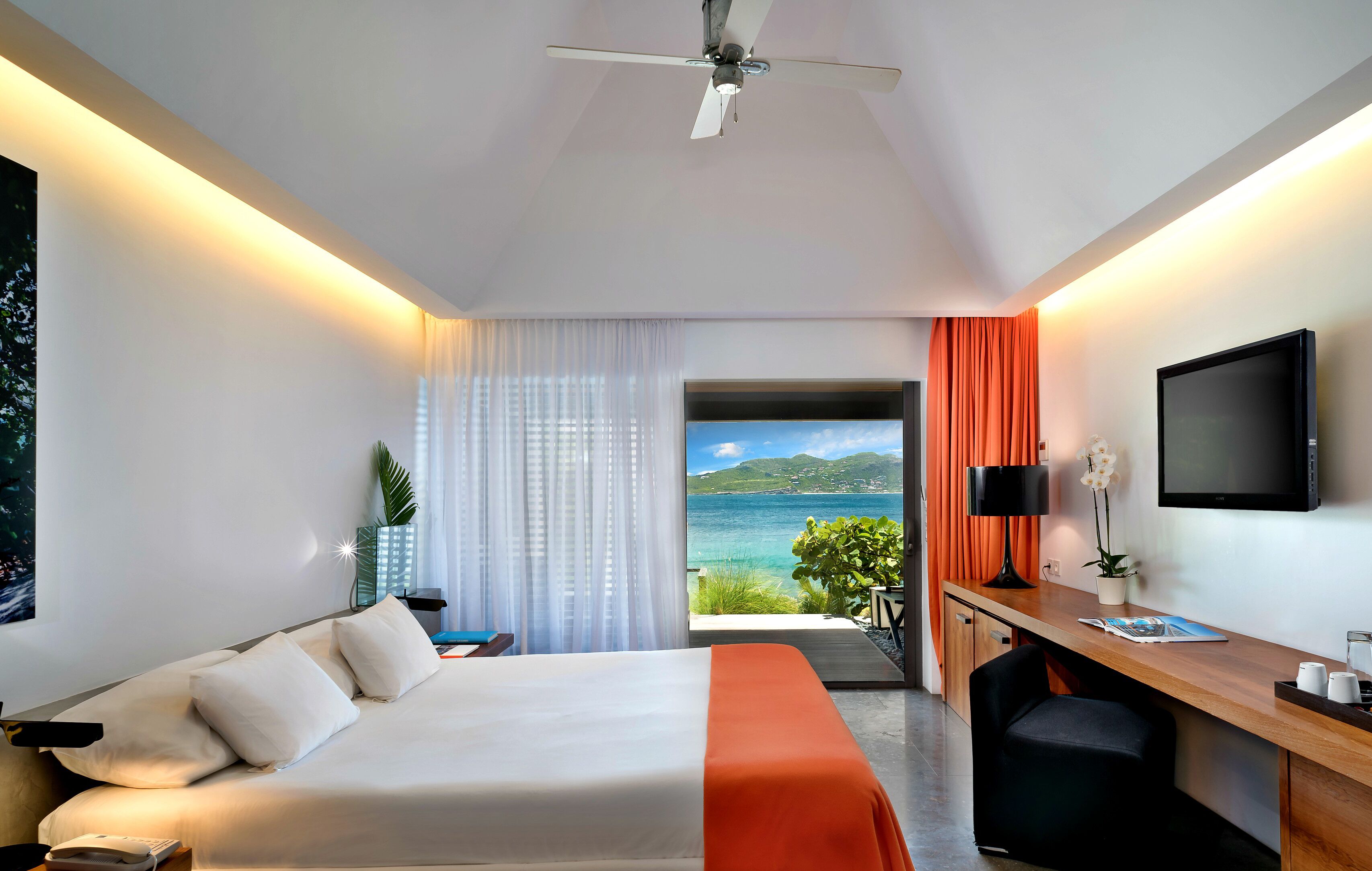 Ein Hotelzimmer mit Bett, Schreibtisch, Fernseher und Meerblick.
