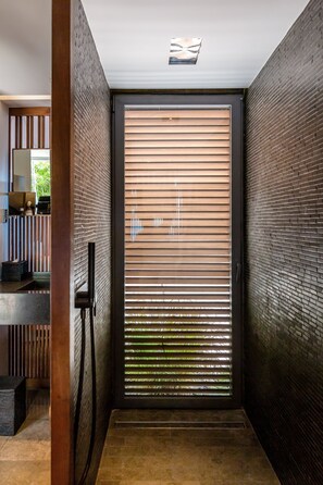 A modern interior with a sliding door, dark brick walls, and a ceiling light fixture.