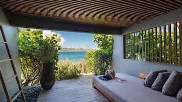 Un dormitorio con vista al mar, una planta grande en maceta y una terraza de madera.