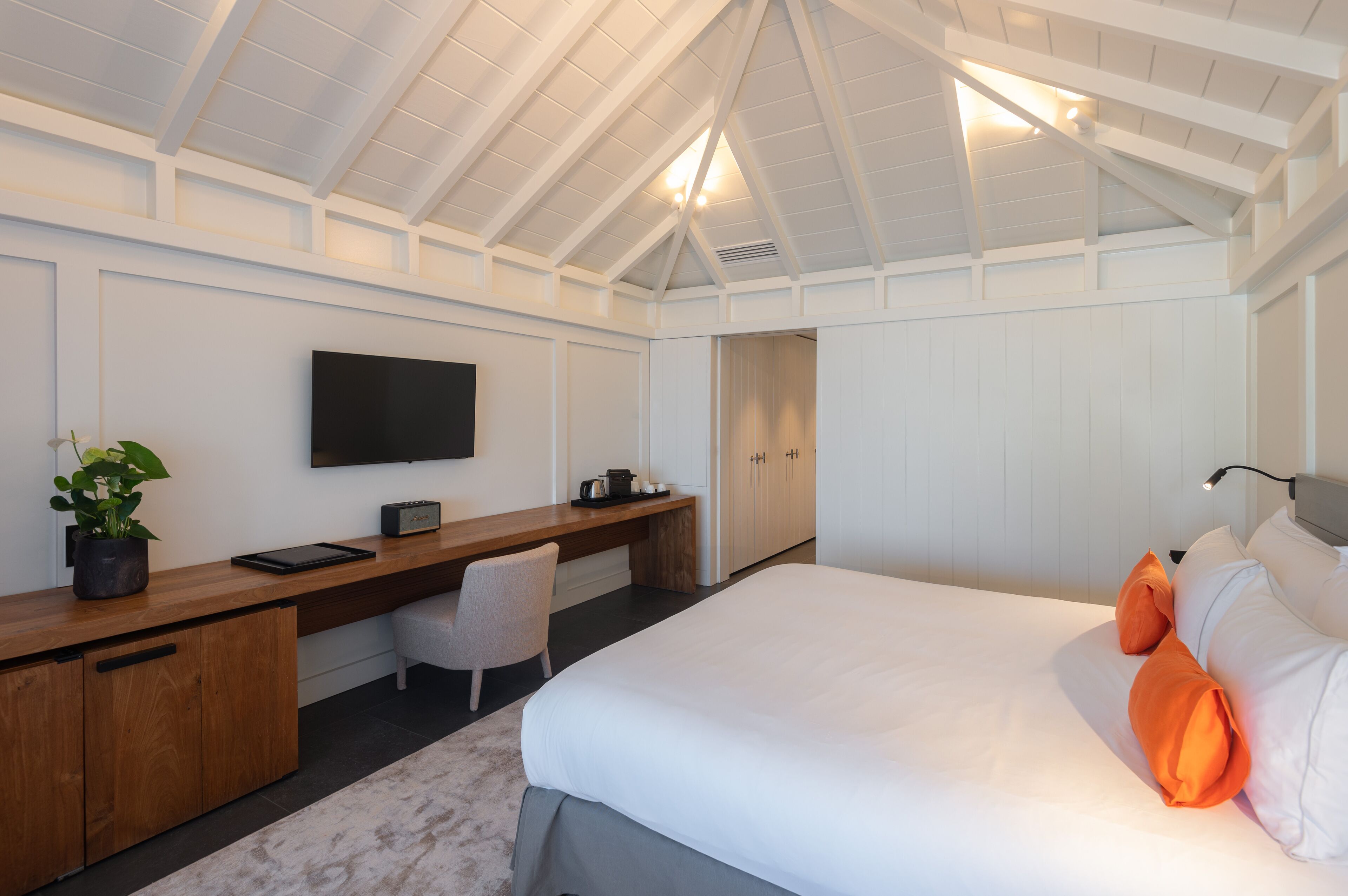 A bedroom with a bed, a desk, a chair, a TV, and a wardrobe.