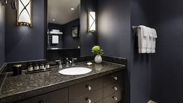 Un baño moderno con una pared oscura, encimera de granito, lavabo blanco y un espejo.