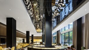 A modern bar area with a central bar, multiple seating options, and a patterned floor. - Fairmont The Queen Elizabeth (Montreal)