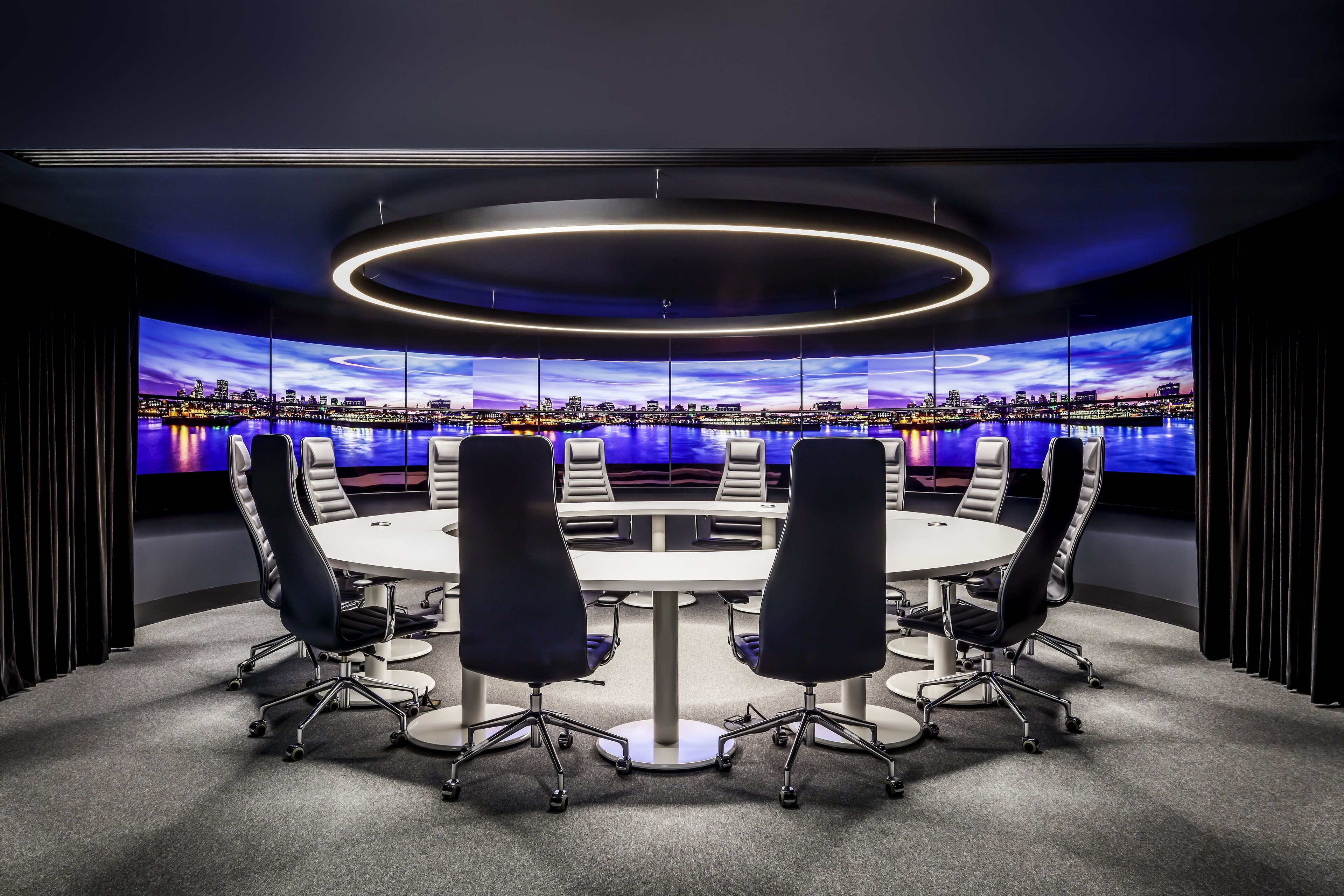 Uma sala de conferências com vista panorâmica da cidade, uma mesa redonda e cadeiras modernas.