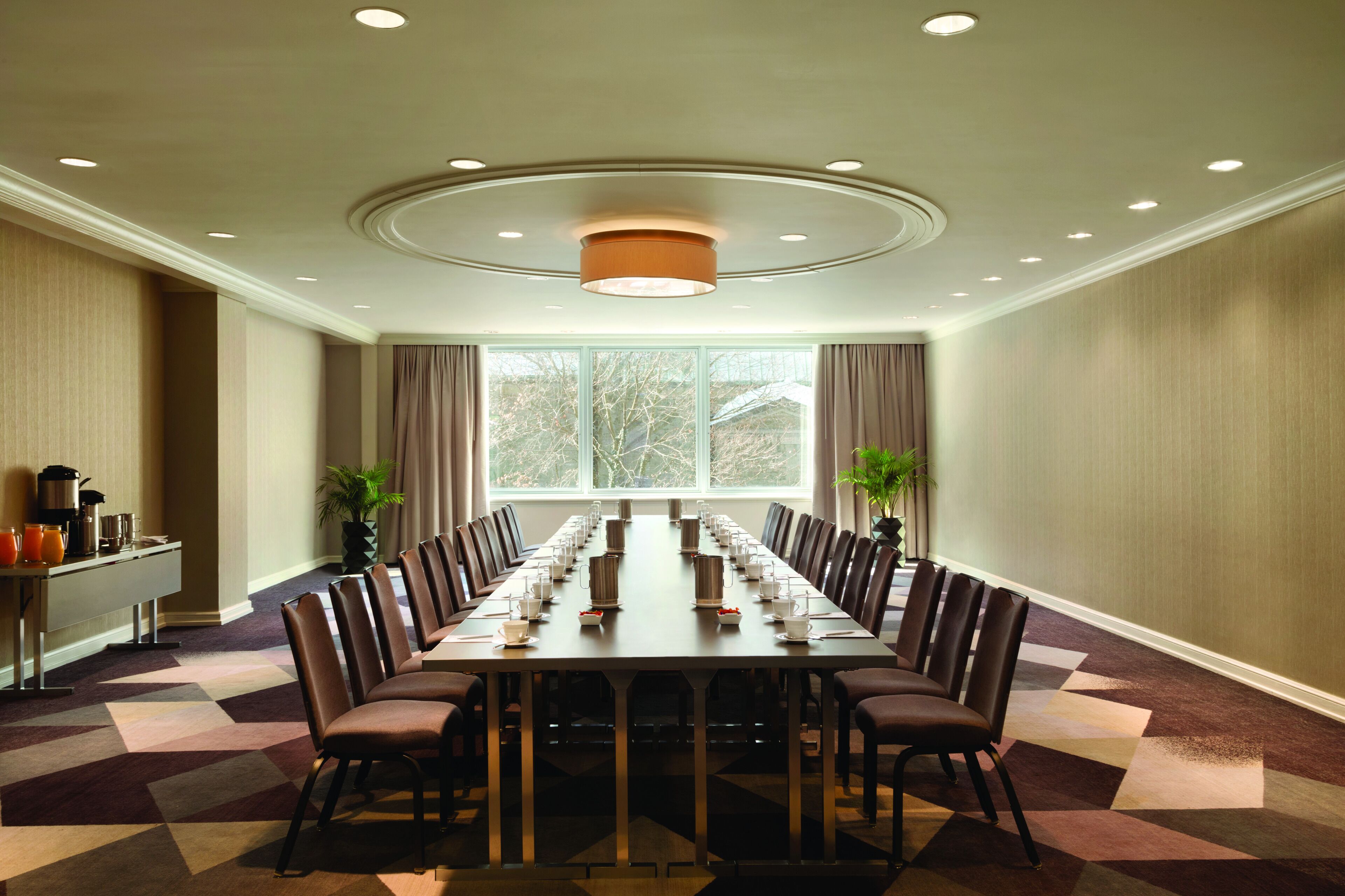 Uma sala de conferências com uma mesa comprida, cadeiras e um espaço para café.