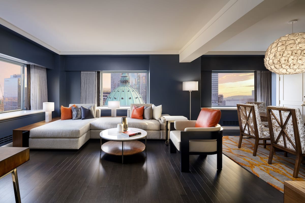A modern living room with a sectional sofa, a round coffee table, and a dining area with chairs and a table.