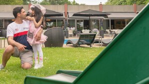 Un hombre y un niño en un parque con mesas al aire libre y sombrillas.