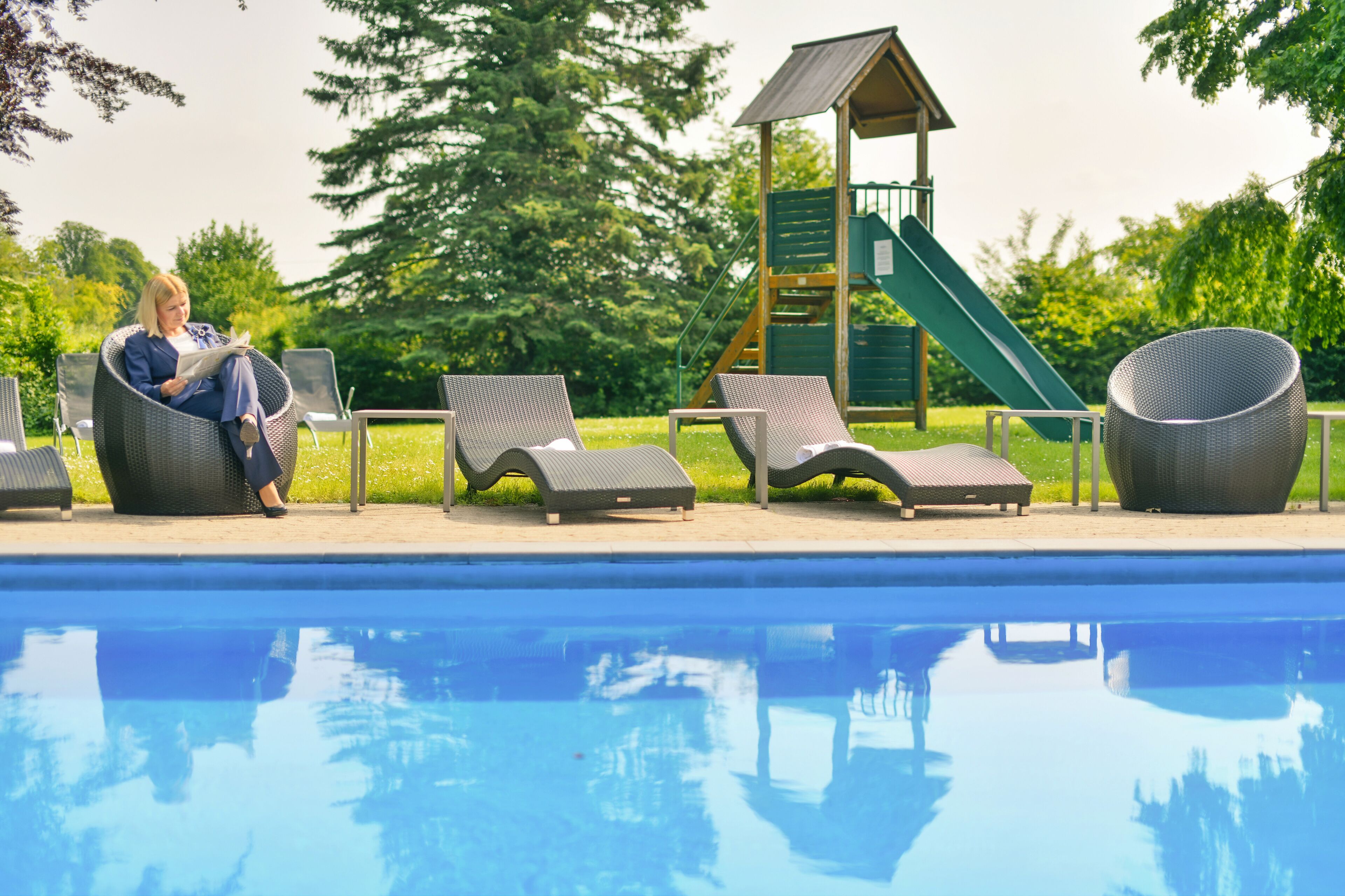 Zona de piscina con sillones de descanso y juegos infantiles.