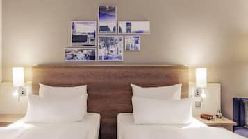 Een hotelkamer met twee bedden, een houten hoofdbord, kunst aan de muur en bedlampjes.