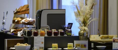 A buffet setup with various food items, a coffee machine, and a decorative vase.