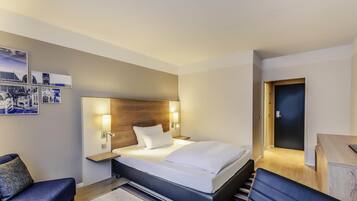 Una habitación de hotel con cama, mesitas de noche, escritorio, silla y puerta.