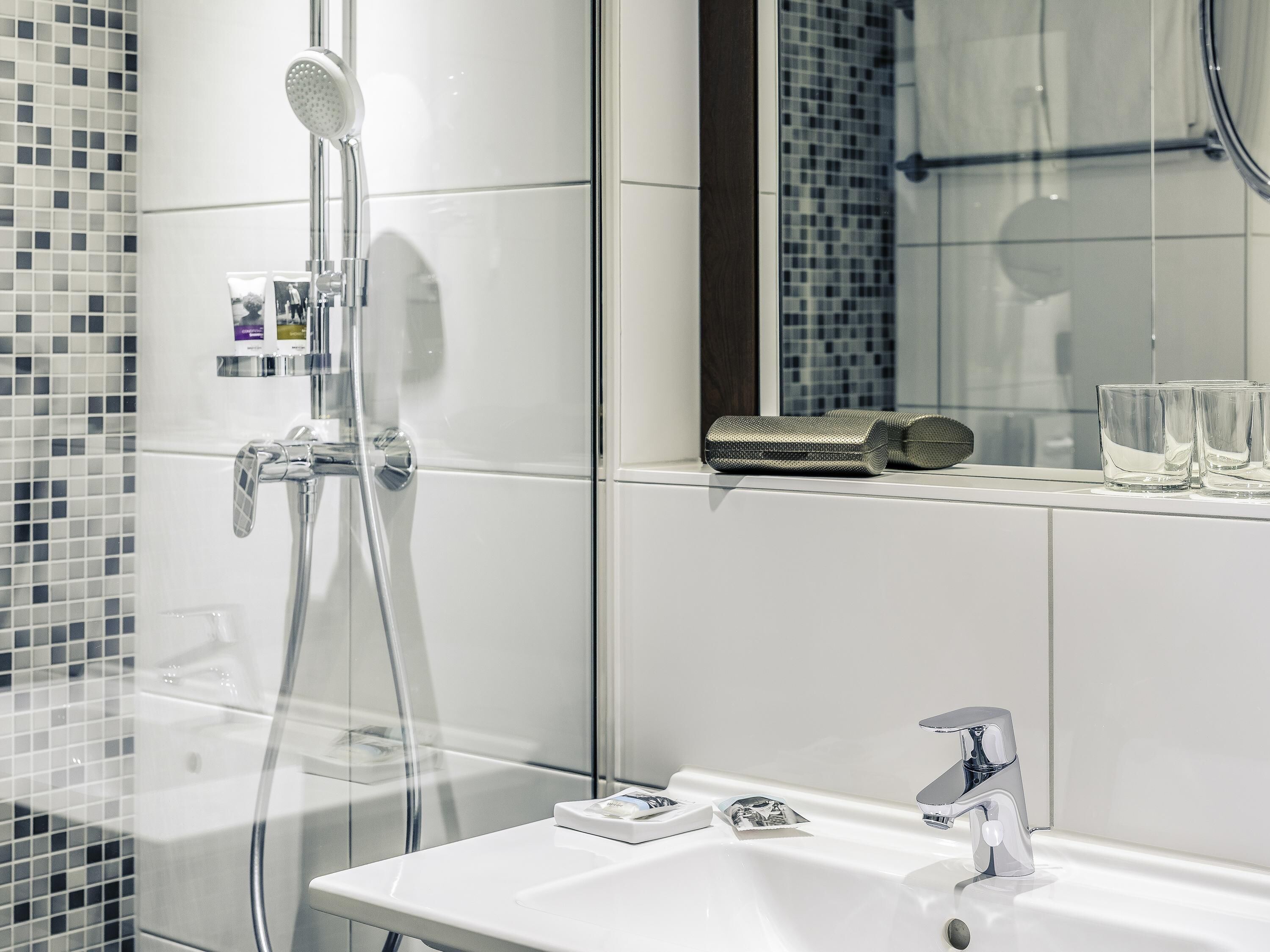A modern bathroom with a glass shower enclosure, a white sink, and a mirror above the sink.