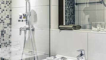 A modern bathroom with a glass shower enclosure, a white sink, and a mirror above the sink.