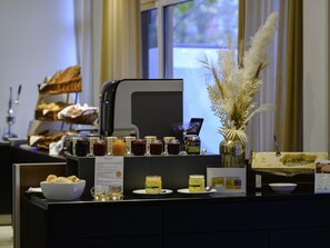 Un buffet proposant une variété de plats, une machine à café et un vase décoratif.