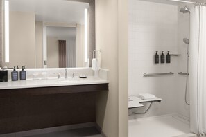 A modern bathroom with a large mirror, a sink with toiletries, and a shower area.
