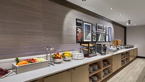 A buffet area with a variety of food items, including fruits, vegetables, and prepared dishes.