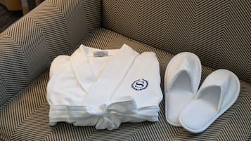 A neatly folded white robe with a monogram on a patterned sofa.