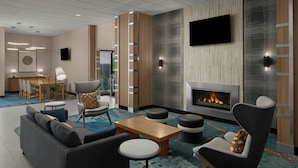 A modern lobby with a fireplace, seating area, and a television.