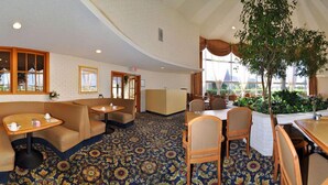 Eine Hotelhalle mit Empfangstresen, Sitzgelegenheiten und einer großen Zimmerpflanze.