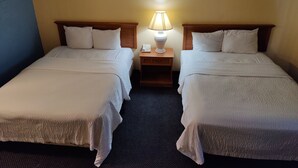 Ein Hotelzimmer mit zwei Einzelbetten, einem Nachttisch mit Lampe und einem Telefon.