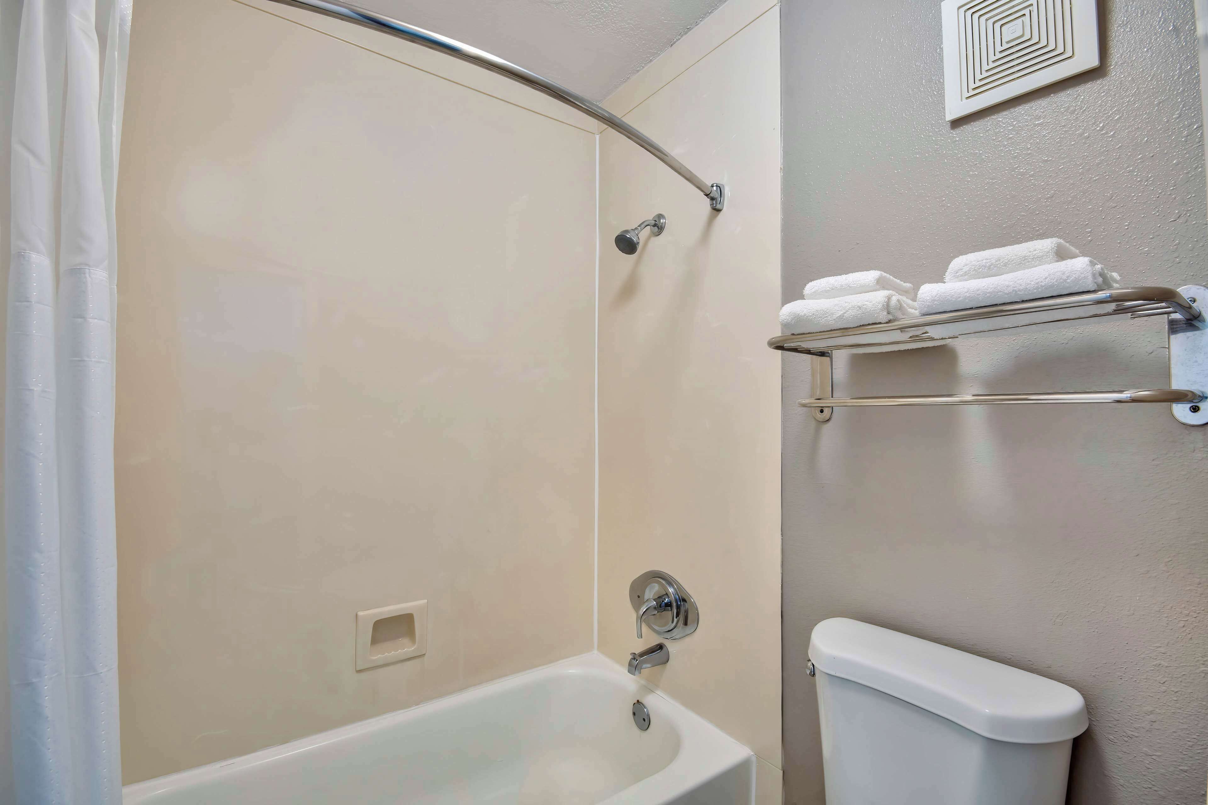 Un baño con ducha, inodoro y toallero.