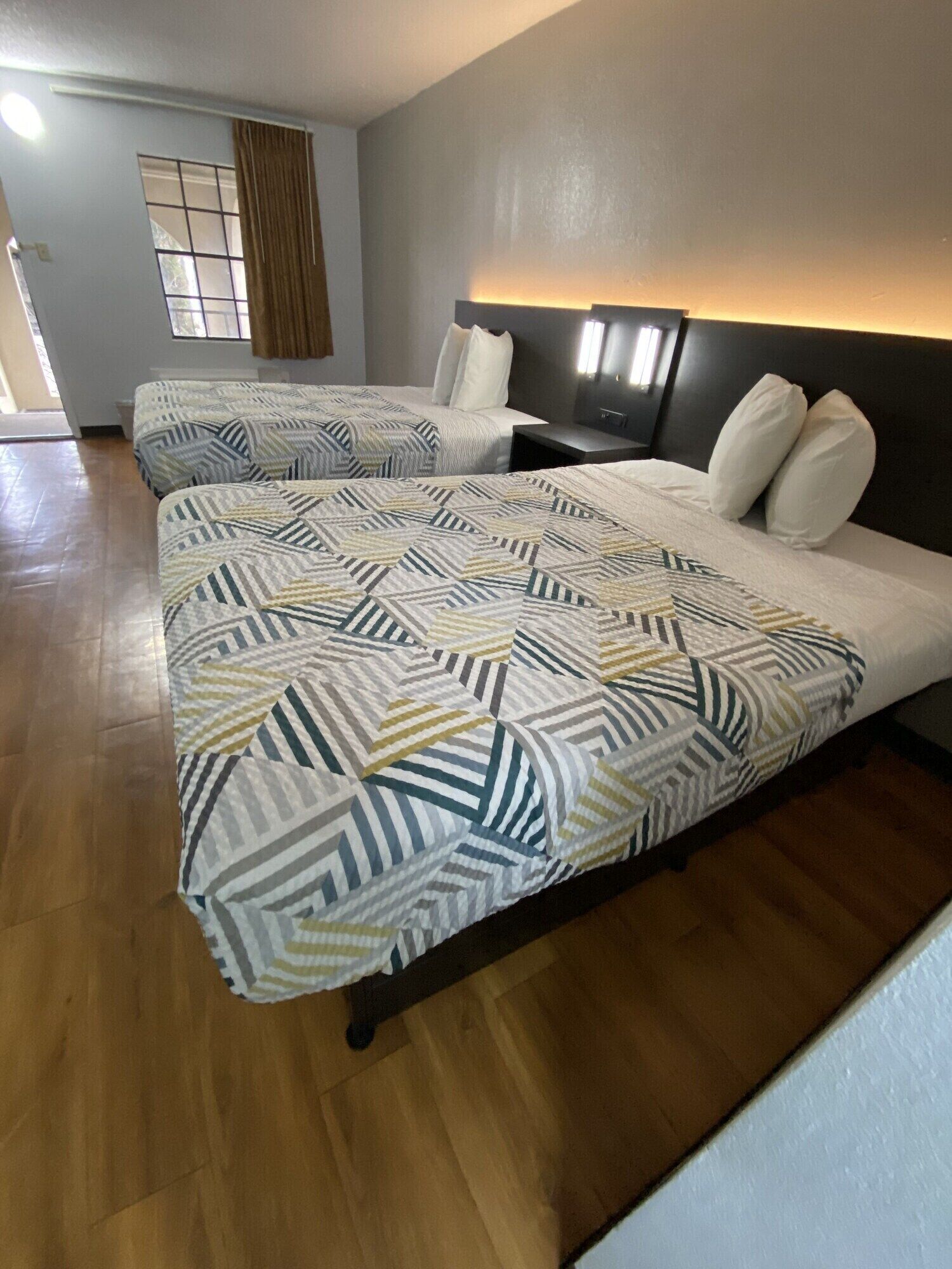 Una habitación de hotel con una cama grande, una mesita de noche y una lámpara fijada a la pared.