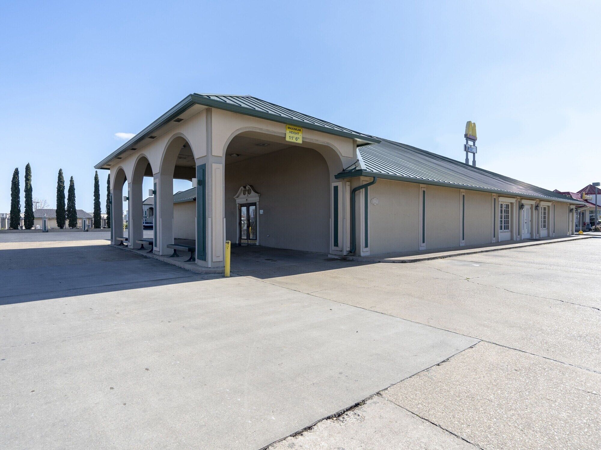 A building with a covered entrance, a sign indicating a maximum height of 11' 6", and a McDonald's sign in the background.