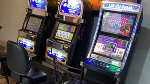 Three slot machines with a chair in front.