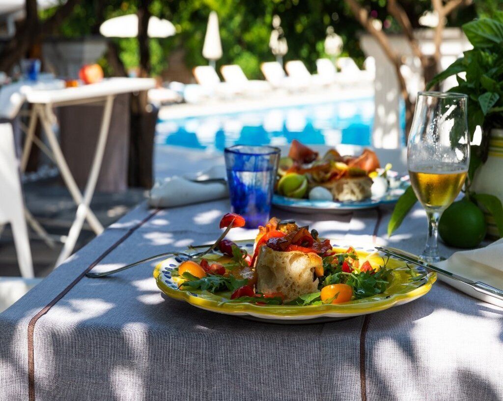 A dining table with a plate of food, a glass of beer, and a glass of water.