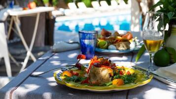 A dining table with a plate of food, a glass of beer, and a glass of water.