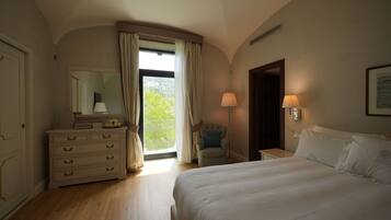 A hotel room with a bed, a dresser, a chair, a lamp, and a window with curtains.
