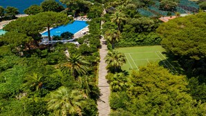 An aerial view of a resort with a swimming pool, tennis court, and lush greenery. - Grand Hotel Cocumella (Sant'Agnello)