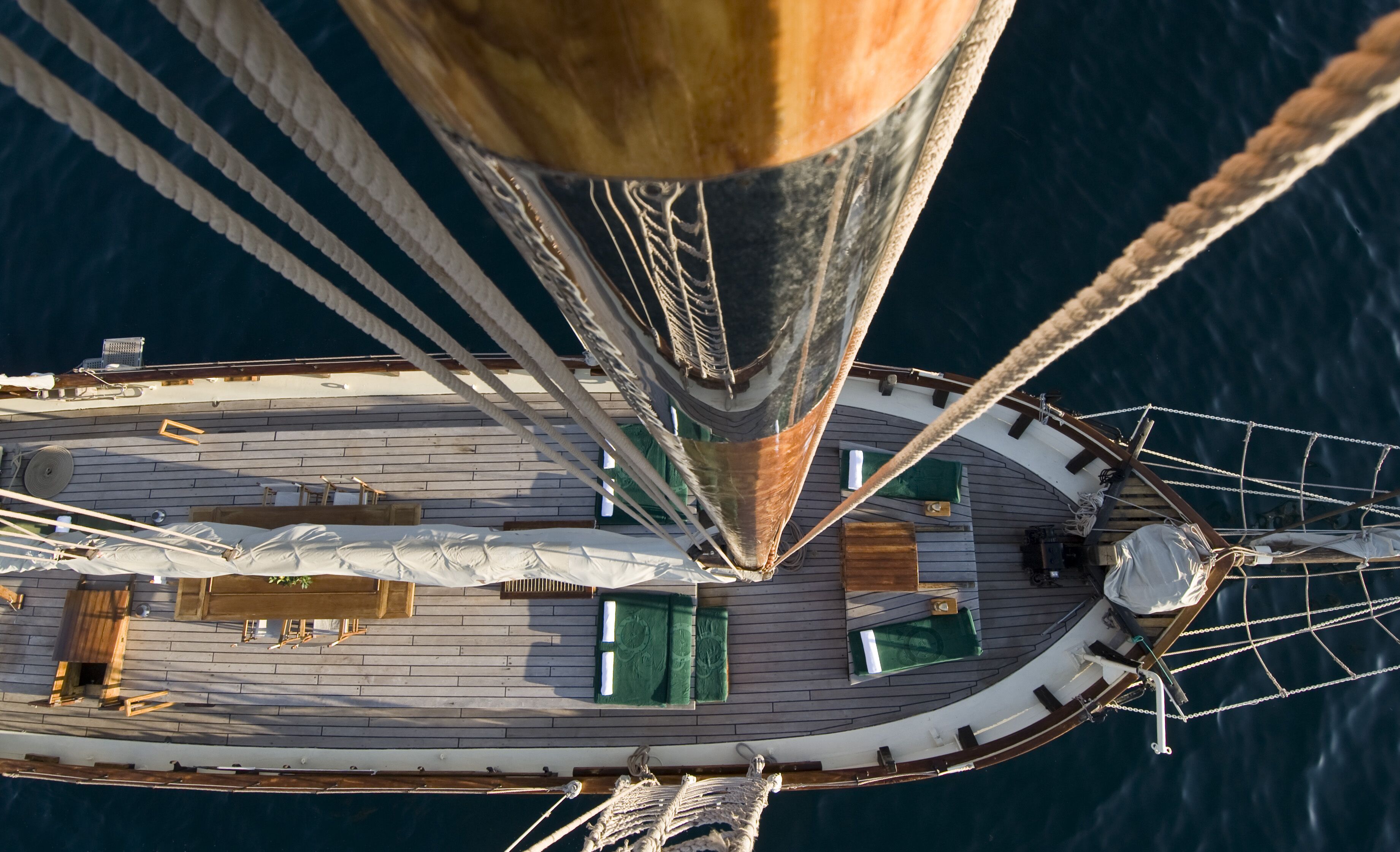 A detailed view of a ship's deck with a wooden cabin layout, a wheel at the stern, and multiple ropes.